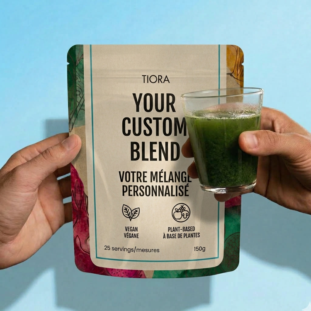 A person holds a stand-up pouch labeled Tiora Your Custom Blend in front of a light blue background, with a hand holding a clear glass of green drink to the right. The pouch has a cream center with black text and multicolored floral-style borders at the sides.